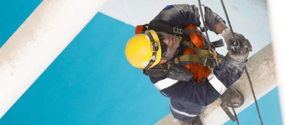 Aerial view of man working in safety gear climbing scaffolding